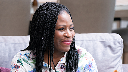 Shawnette, smiling in floral shirt, looking away.